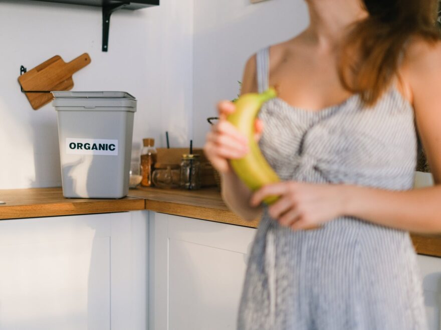 crop woman with organic banana in hands standing in kitchen