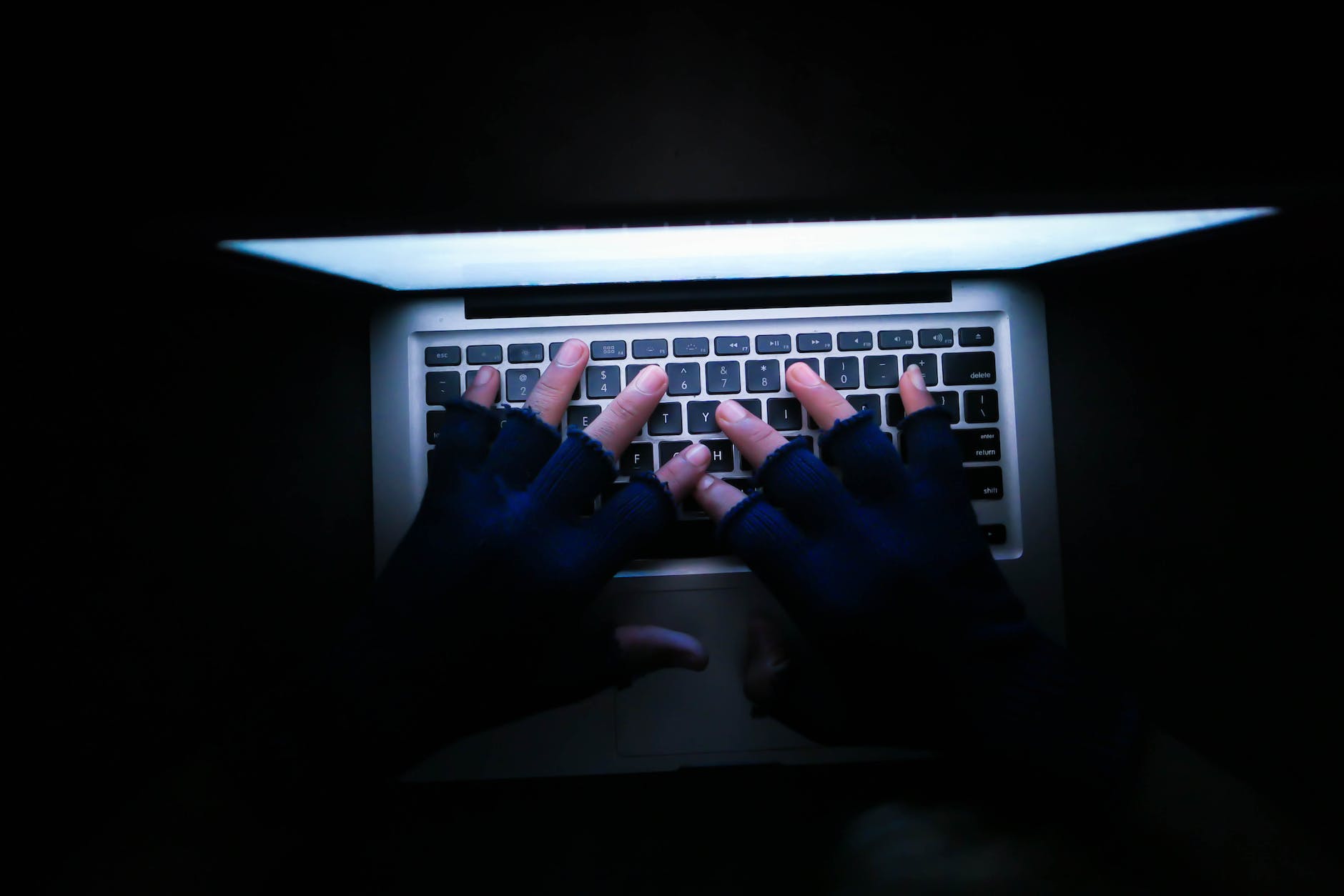 high angle shot of a person wearing carpal tunnel gloves while using a laptop computer